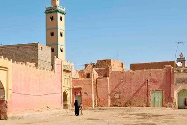 Colorido zoco marroquí en Marruecos con arquitectura tradicional y mezquita en el fondo.